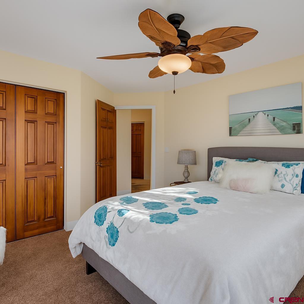 1711 Golf Course Lane Cortez, CO 81321 - Photo 26 of 45 a bedroom with a bed ceiling fan and a wooden floor
