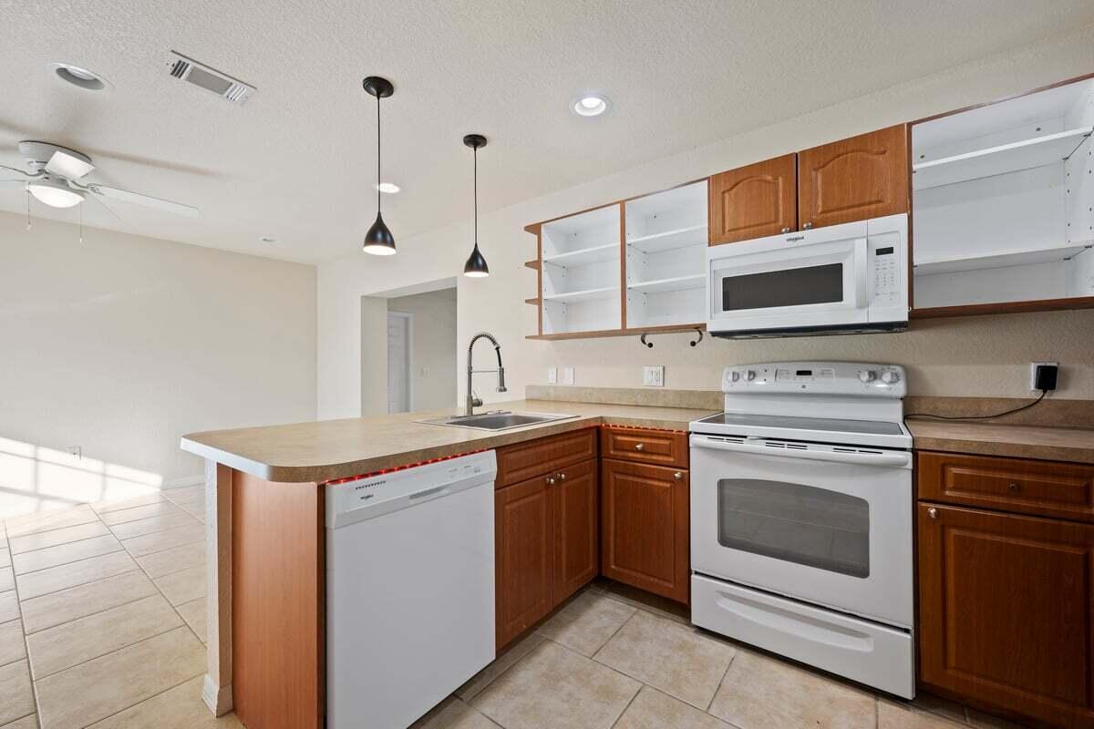 1875 45th Avenue Vero Beach, FL 32966 - Photo 5 of 14 a kitchen with stainless steel appliances granite countertop a kitchen island a stove a sink and a microwave