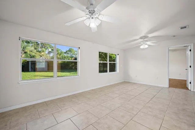 a view of an empty room with a window and a ceiling fan