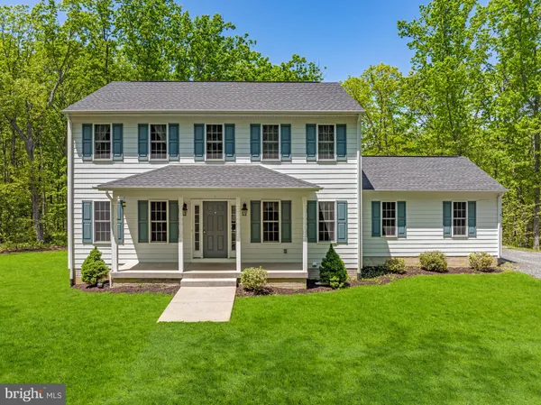 a front view of a house with a yard and green space