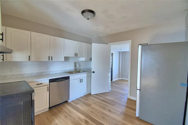 a kitchen with granite countertop a sink cabinets and wooden floor