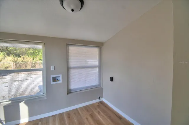 a view of an empty room with wooden floor and a window