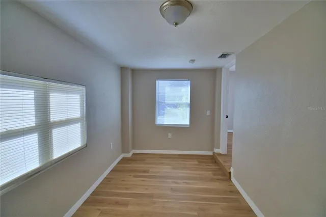 a view of a hallway with wooden floor and closet