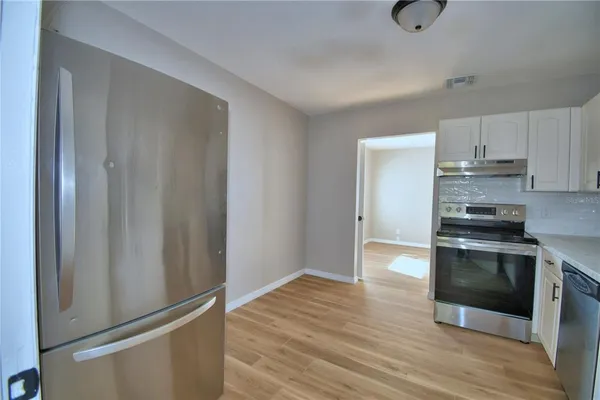 a kitchen with granite countertop a refrigerator and a stove top oven