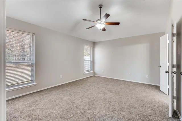 an empty room with windows and fan