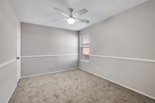 an empty room with windows and ceiling fan