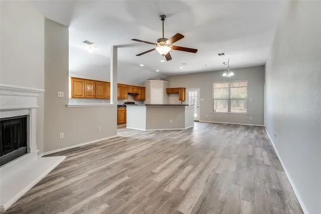an empty room with kitchen and wooden floor