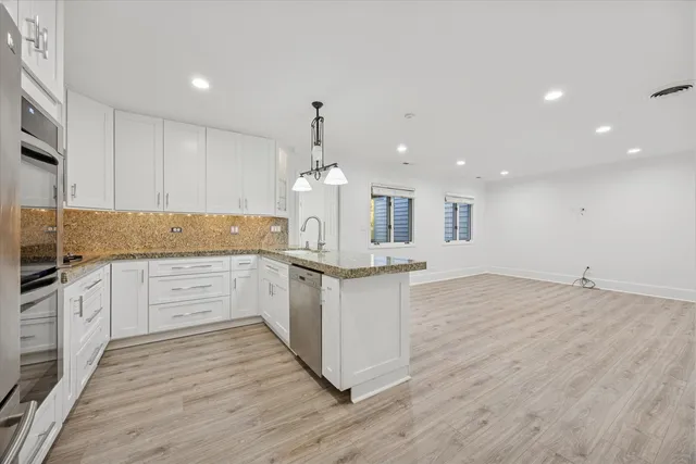 a large kitchen with granite countertop a large counter top stainless steel appliances and cabinets