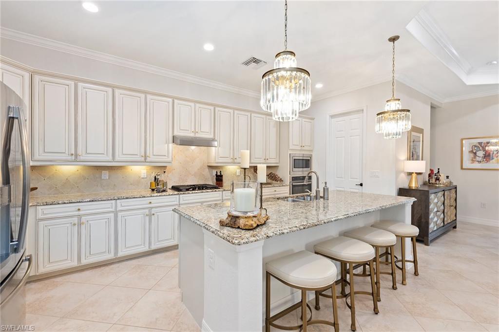 2806 Aviamar Circle Naples, FL 34114 - Photo 4 of 50 a kitchen with stainless steel appliances a table chairs and cabinets