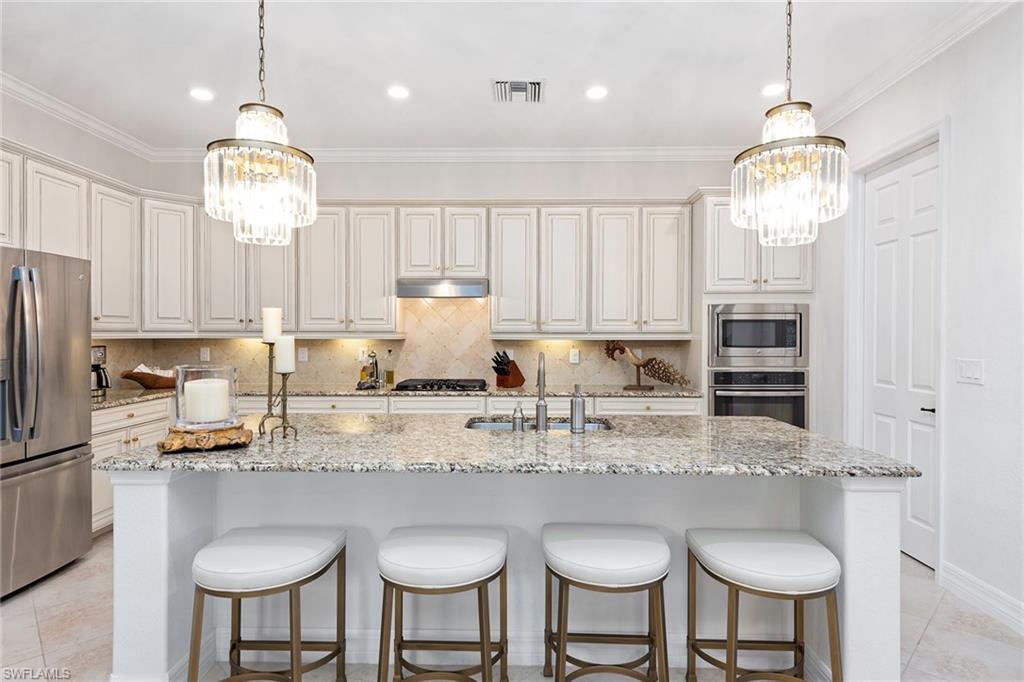 2806 Aviamar Circle Naples, FL 34114 - Photo 5 of 50 a kitchen with stainless steel appliances granite countertop a dining table chairs stove and refrigerator