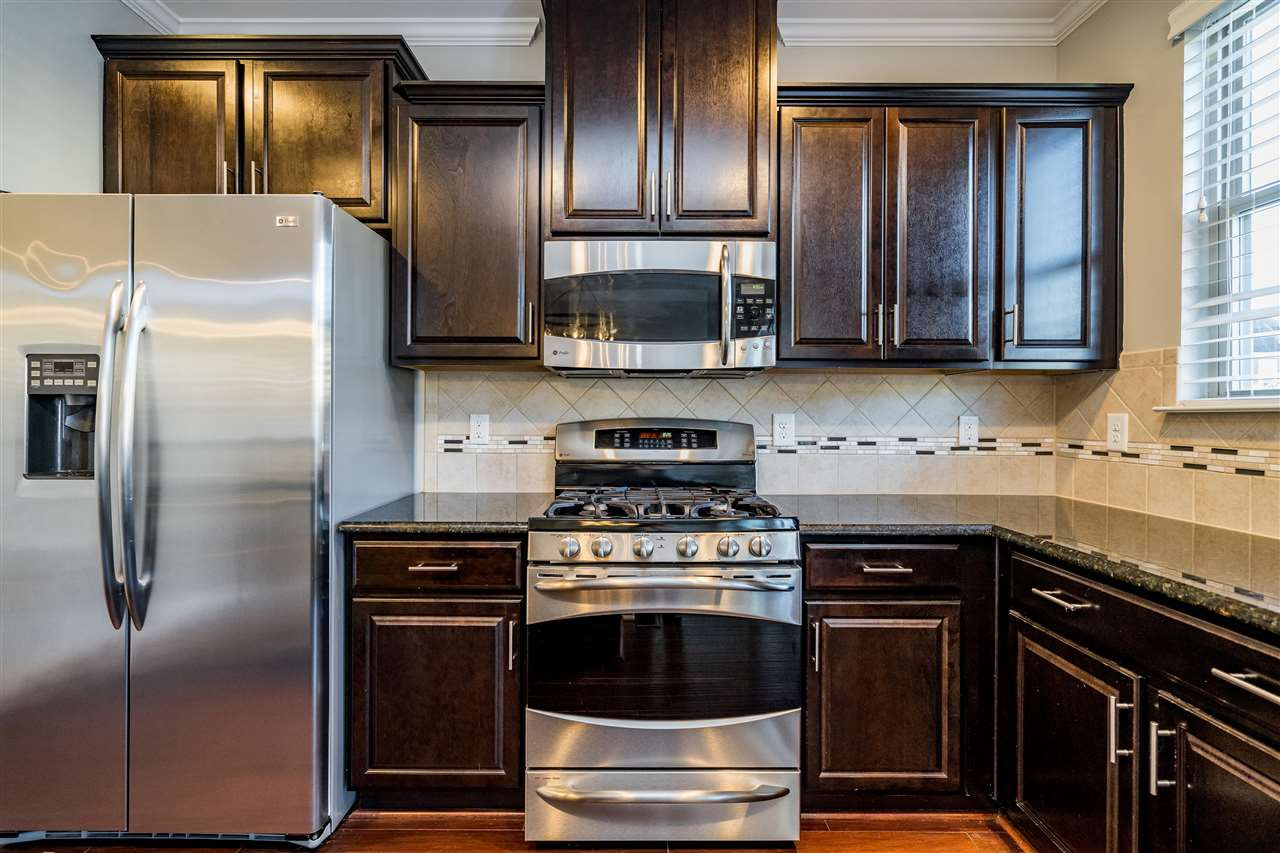 1521 Rodessa Run Raleigh, NC 27607 - Photo 18 of 29 Kitchen features easy island/bar for eating/cooking/hanging out. Granite counters, stainless appliances, full pantry with wooden shelving, ceramic tile backsplash and the loved dark cabinets. Kitchen