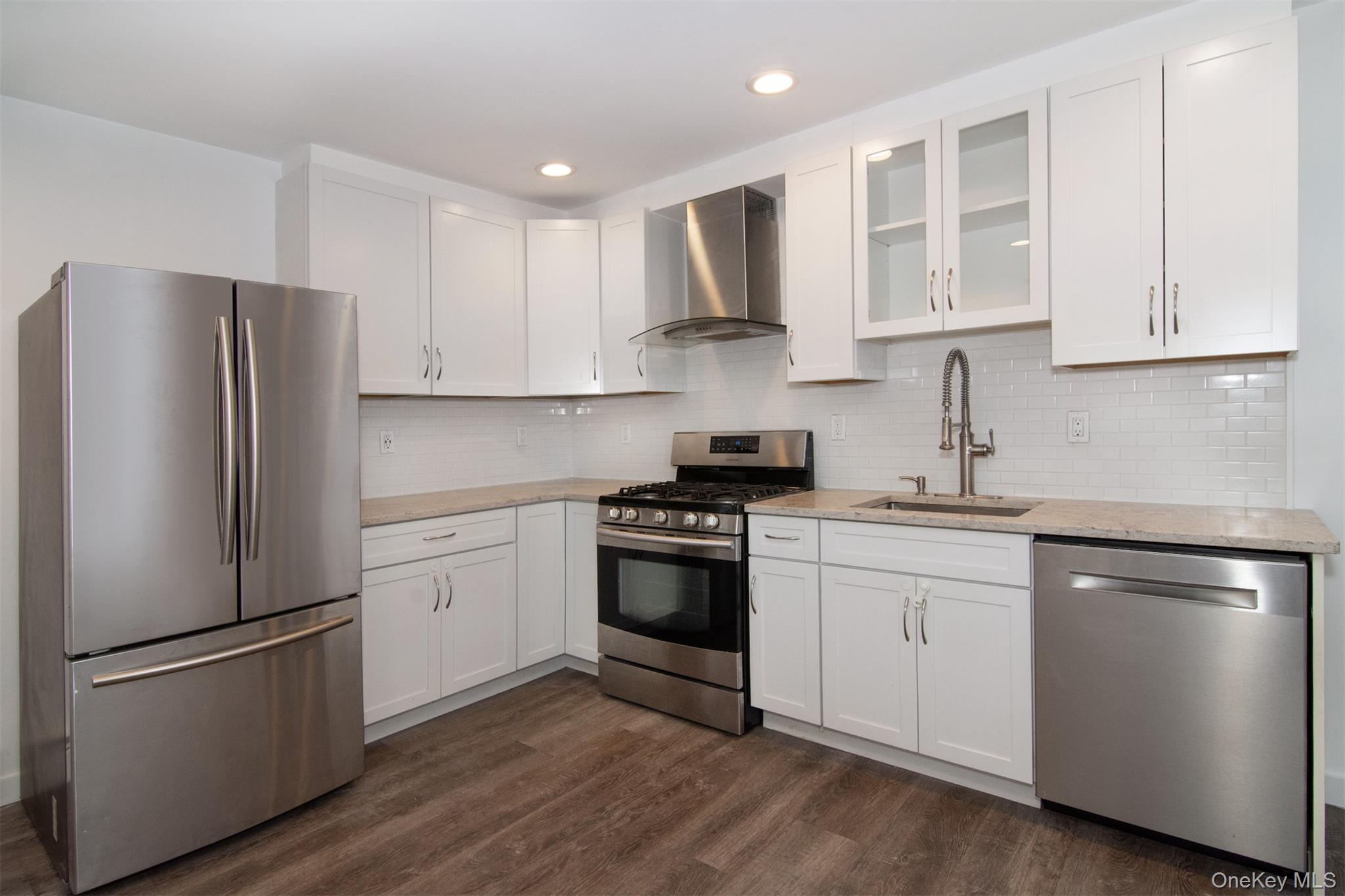 44 Ridge Street, Unit 1 Hastings-on-Hudson, NY 10706 - Photo 2 of 16 Kitchen featuring appliances with stainless steel finishes, dark hardwood / wood-style flooring, white cabinets, wall chimney range hood, and sink