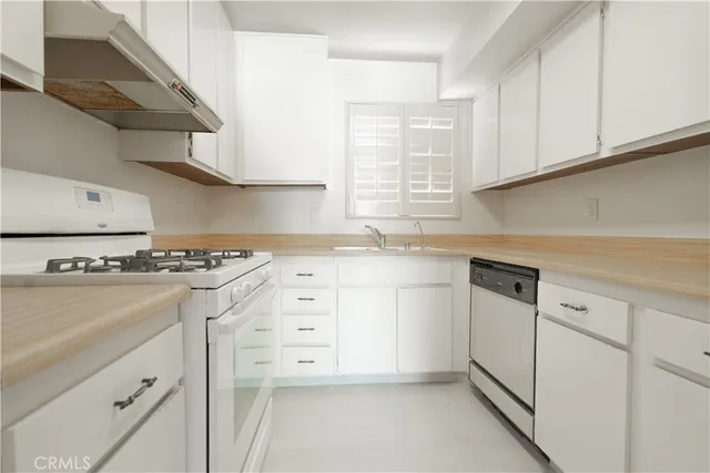 a kitchen with granite countertop white cabinets and white appliances