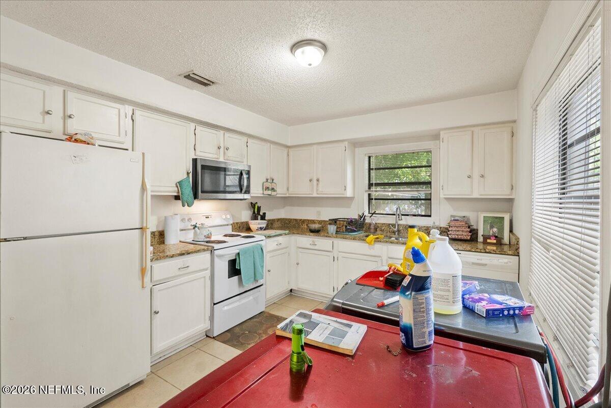 2910 Post Street Jacksonville, FL 32205 - Photo 22 of 34 a kitchen with a refrigerator a stove a sink dishwasher and white cabinets with wooden floor