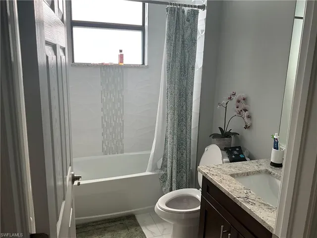 a bathroom with a granite countertop sink a toilet and shower