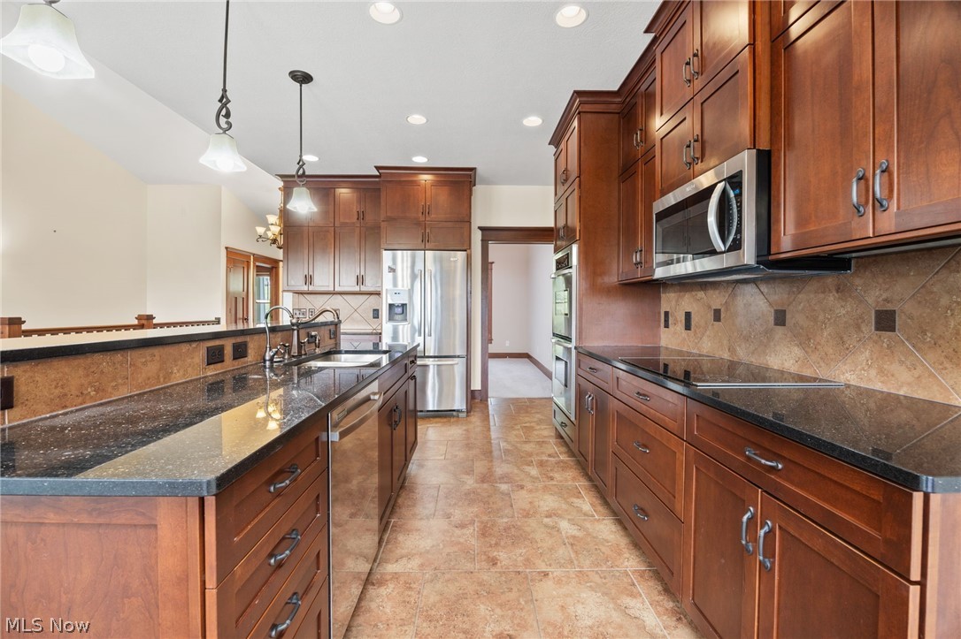 6925 River Styx Road Medina, OH 44256 - Photo 10 of 49 Kitchen featuring rich wood cabinetry, dark countertops, stainless steel appliances, ceramic tile flooring, and pendant lighting fixtures