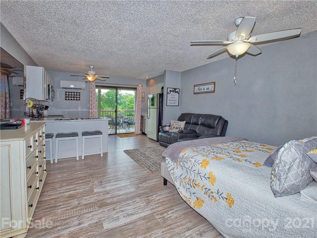 160 Whitney Boulevard, Unit 65 Lake Lure, NC 28746 - Photo 4 of 21 a bedroom with a large bed and a chandelier