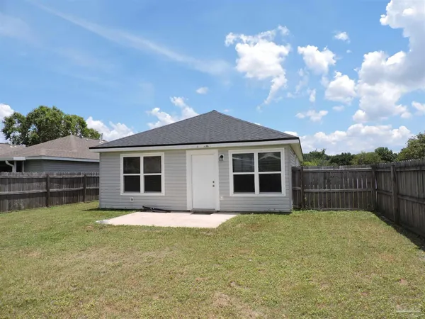 a front view of house with yard and trees in the background