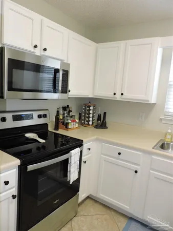 a kitchen with white cabinets and black appliances
