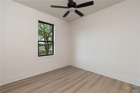 an empty room with a window and a ceiling fan