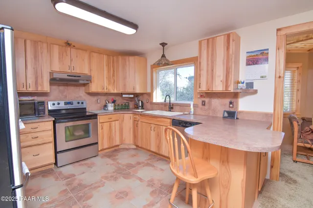 a kitchen with stainless steel appliances granite countertop a sink a stove a refrigerator cabinets and a window