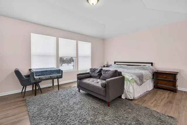 a spacious bedroom with a bed and wooden floor