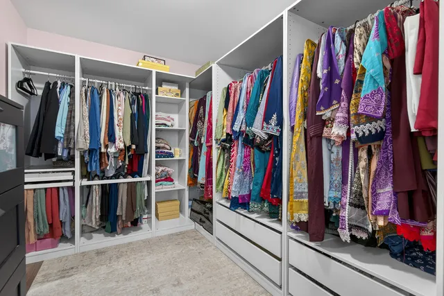 a view of walk in closet with clothes and shoes