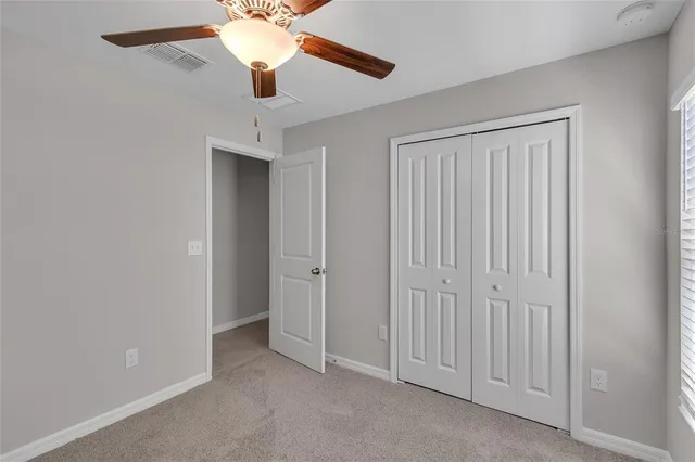 an empty room with a chandelier fan and windows