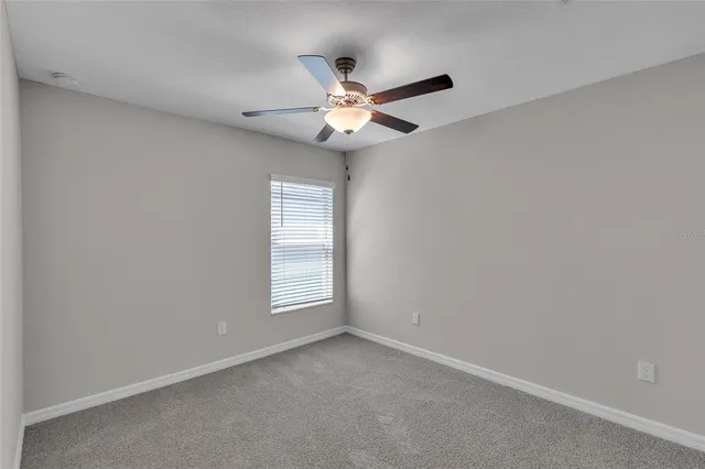 an empty room with a chandelier fan and closet