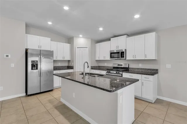 a large kitchen with stainless steel appliances granite countertop a sink a stove and cabinets