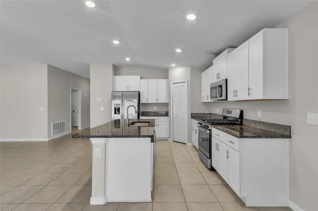 a kitchen with granite countertop white cabinets white stainless steel appliances and a sink