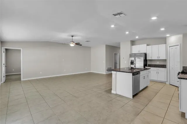 a view of an empty room with a chandelier fan