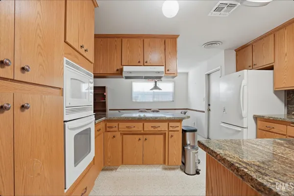 a kitchen with stainless steel appliances granite countertop a refrigerator a stove and a sink
