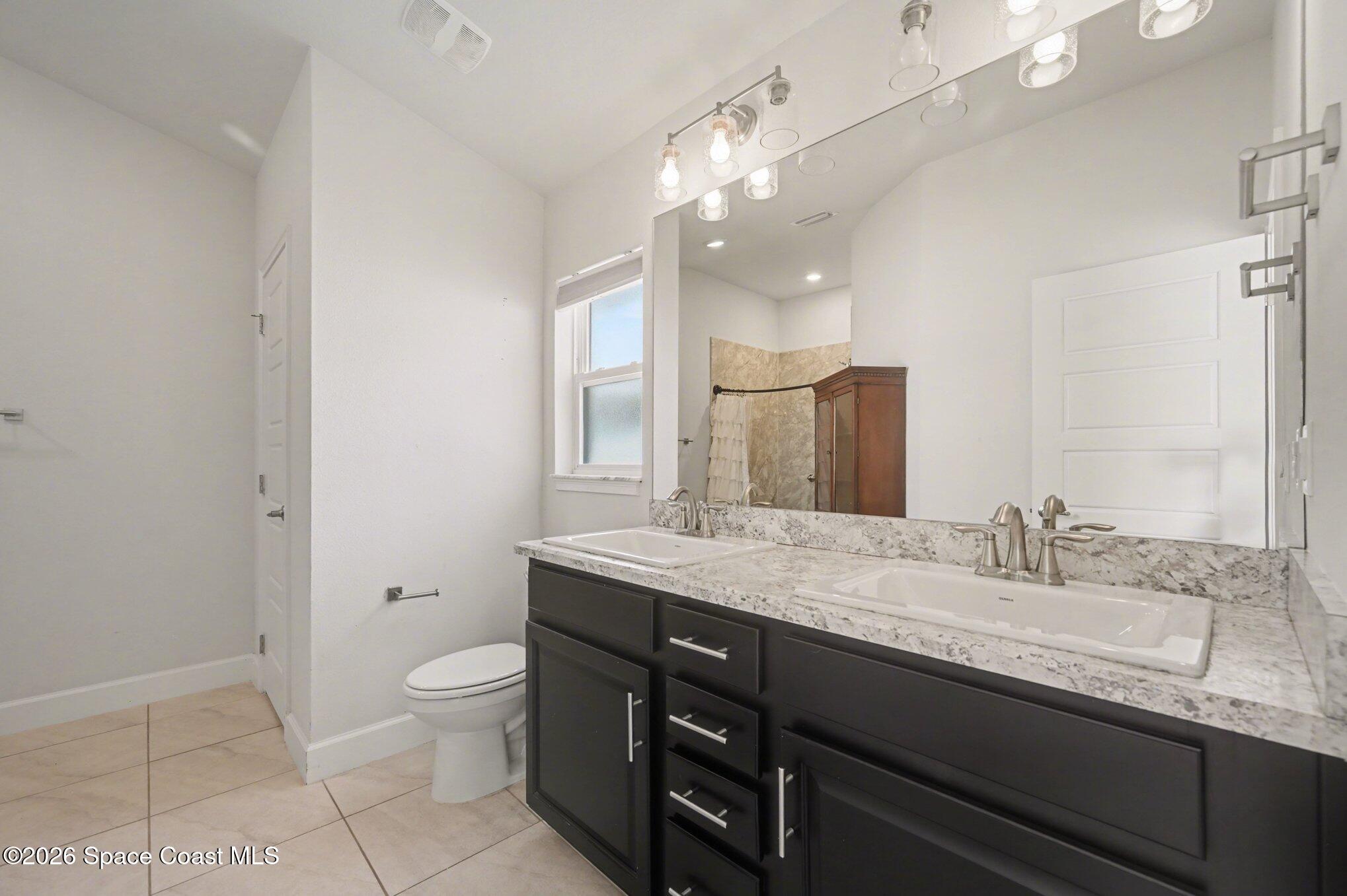 831 Tupelo Circle Cocoa, FL 32926 - Photo 16 of 23 a bathroom with a granite countertop sink a toilet and a mirror