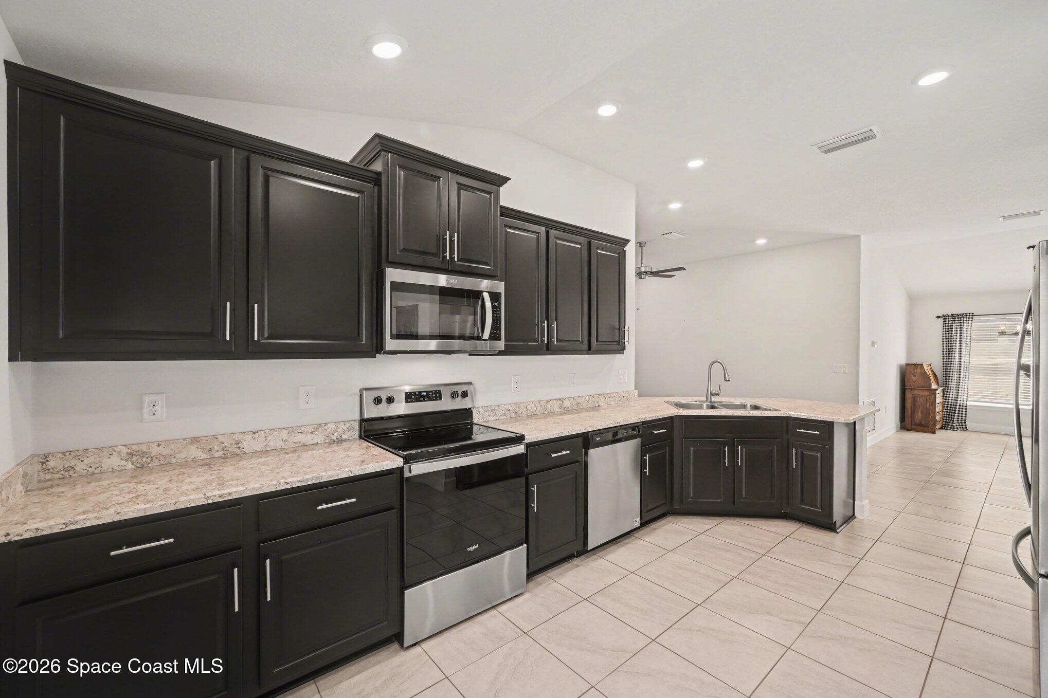 831 Tupelo Circle Cocoa, FL 32926 - Photo 5 of 23 a kitchen with stainless steel appliances granite countertop a sink and stove top oven with wooden cabinets