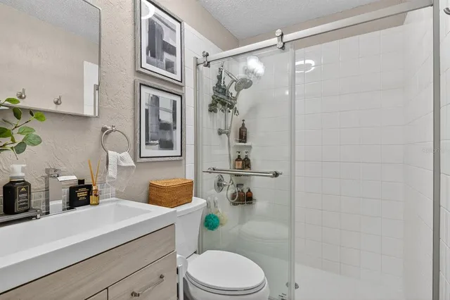 a bathroom with a sink vanity granite toilet and shower