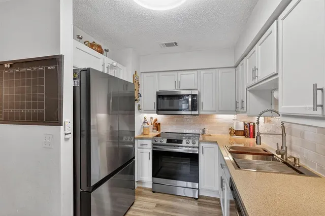 a kitchen with stainless steel appliances granite countertop a refrigerator stove and sink