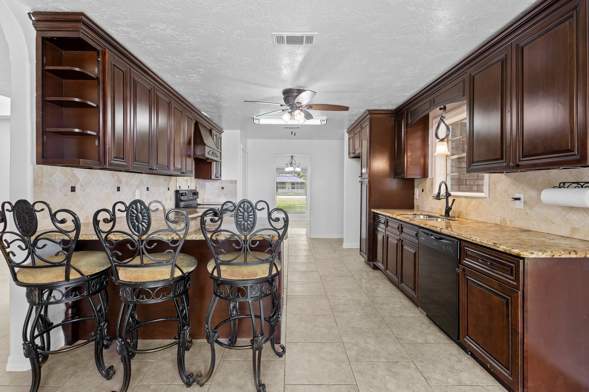 6281 25th Street Groves, TX 77619 - Photo 4 of 26 a kitchen with granite countertop stainless steel appliances lots of wooden cabinets a sink stove and chairs