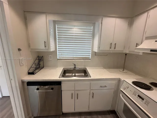 a kitchen with cabinets appliances a sink and a window