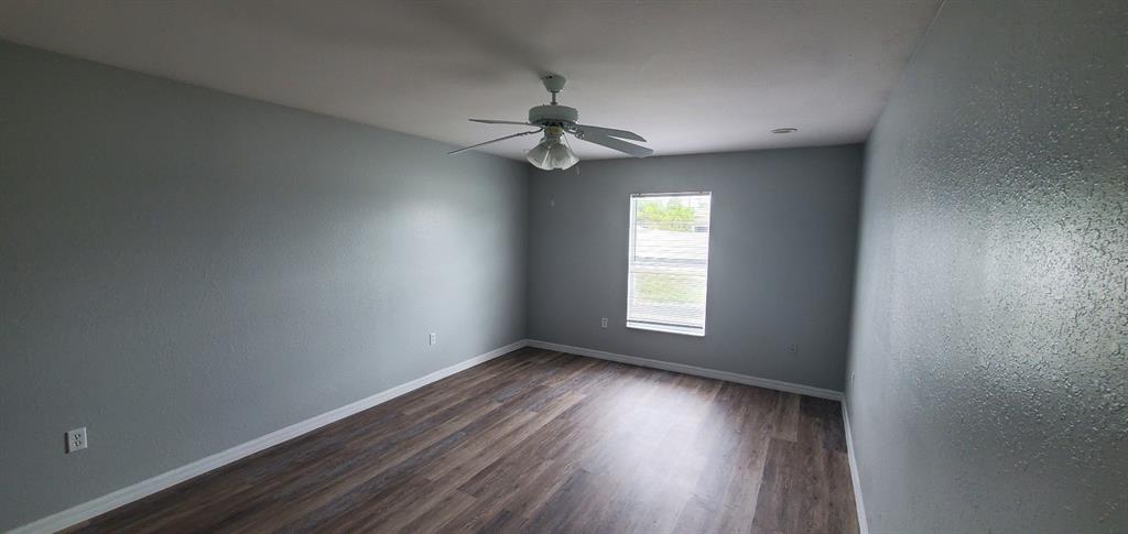 1757 Pompano Drive Kissimmee, FL 34759 - Photo 12 of 14 an empty room with wooden floor ceiling fan and windows