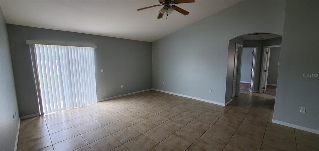 1757 Pompano Drive Kissimmee, FL 34759 - Photo 4 of 14 an empty room with a ceiling fan and carpet