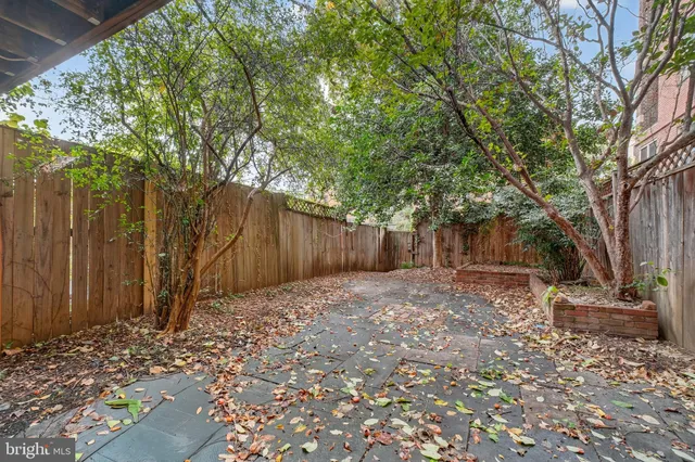 a backyard of a house with large trees and wooden fence