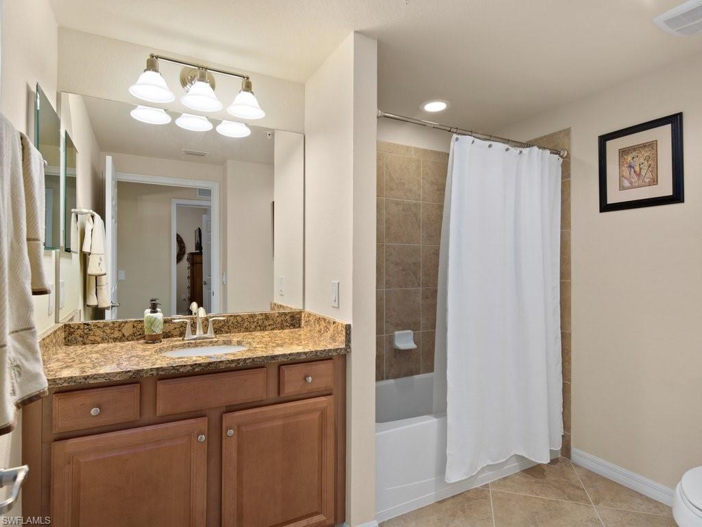 9118 Prima Way, Unit 101 Naples, FL 34113 - Photo 19 of 22 a bathroom with a granite countertop sink a mirror and a shower