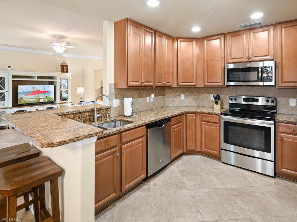 9118 Prima Way, Unit 101 Naples, FL 34113 - Photo 9 of 22 a kitchen with stainless steel appliances granite countertop a stove sink and microwave