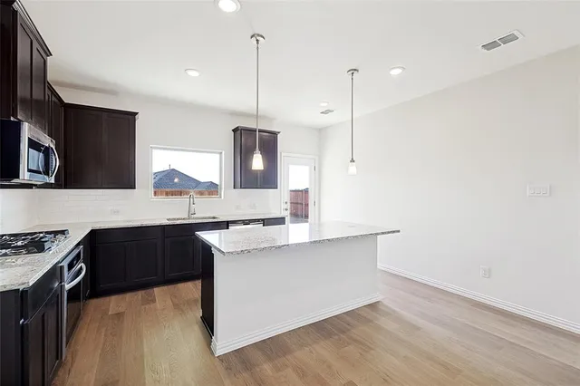 a kitchen with a sink a stove and a wooden floor