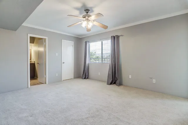 an empty room with chandelier fan and windows