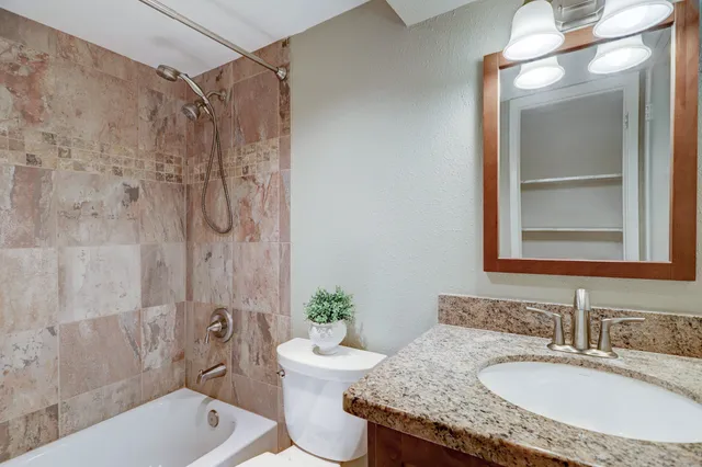 a bathroom with a granite countertop sink a toilet and shower