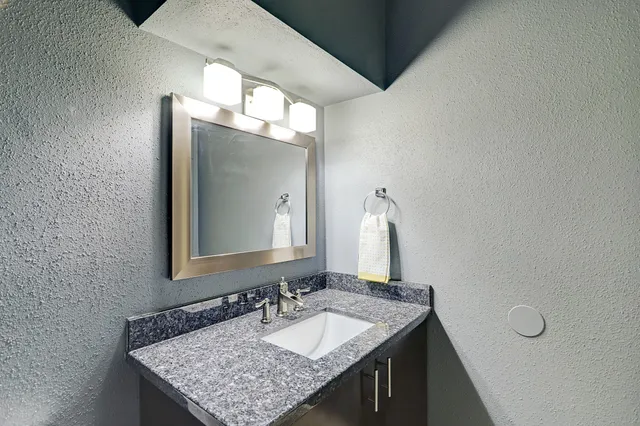 a bathroom with a granite countertop sink and a mirror