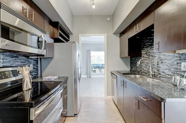 a kitchen with stainless steel appliances granite countertop a sink stove and refrigerator