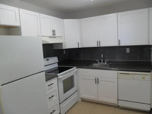 a kitchen with granite countertop white cabinets and white appliances